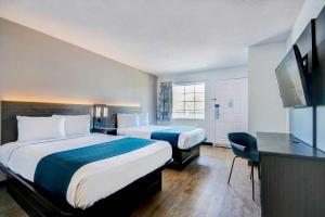 um quarto de hotel com duas camas e uma televisão de ecrã plano em Studio 6-Ocean Springs, MS em Ocean Springs