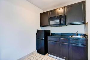 a kitchen with black cabinets and a black refrigerator at Studio 6-Ocean Springs, MS in Ocean Springs