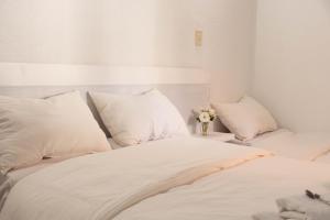 ein weißes Bett mit weißen Kissen und einer Blumenvase in der Unterkunft El Bonito Salta in Salta + 21 Fotos
