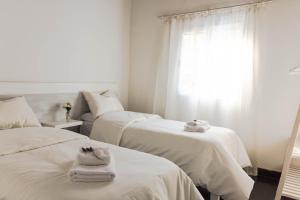 zwei Betten in einem Zimmer mit weißer Bettwäsche und Handtüchern in der Unterkunft El Bonito Salta in Salta