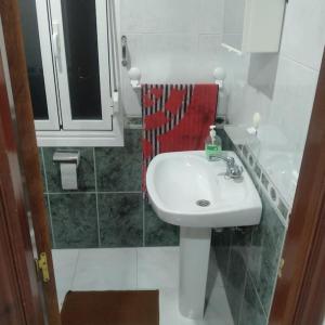 baño con lavabo blanco y toalla roja en A Casa da Esquina, en Portomarín