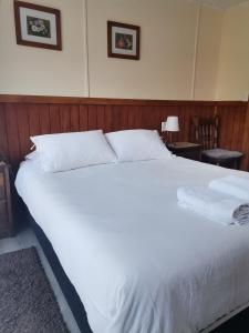 1 cama grande con sábanas y almohadas blancas en Departamento Rossbach en Puerto Puyuhuapi