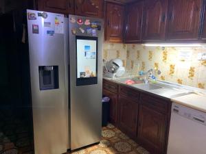 a stainless steel refrigerator in a kitchen with wooden cabinets at Joe's House in Fátima