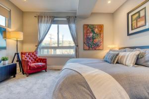 ein Schlafzimmer mit einem Bett und einem roten Stuhl und einem Fenster in der Unterkunft Walk to Empower Field Townhome with Hot Tub! in Denver