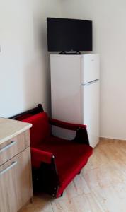 a red chair in a kitchen with a white refrigerator at Ενοικιαζόμενα Δωμάτια Γεωργία Σταμούλου in Rovies