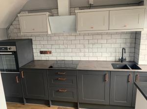 a kitchen with gray cabinets and white appliances at cozy room Shared House in Bristol +8 photos