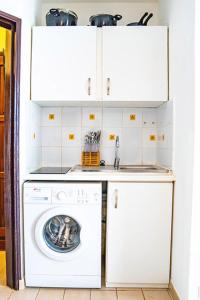 uma máquina de lavar roupa numa cozinha com armários brancos em Bel appartement T2 * Netflix * Terrasse* Parking em Kourou