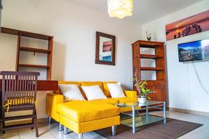 uma sala de estar com um sofá amarelo e uma mesa em Bel appartement T2 * Netflix * Terrasse* Parking em Kourou