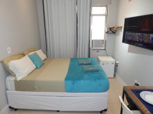een kleine kamer met een bed, een televisie en een televisie bij Flat Atlântica na Orla de Copacabana POSTO 6 in Rio de Janeiro