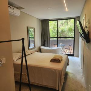 um quarto com uma cama, uma banheira e uma janela em Casa Arrô - Pousada Boutique em Itajaí
