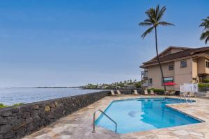 a swimming pool with a retaining wall next to the water at Sea Village #3202 in Kailua-Kona