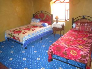 1 dormitorio con 2 camas y 1 mesa con ventana en DAR Awlim en Amassa