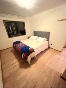 a bedroom with a large bed with a wooden floor at Casa en Farellones in Santiago