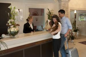 a man and a woman standing at a counter with a dog at Hotel Corsignano in Pienza