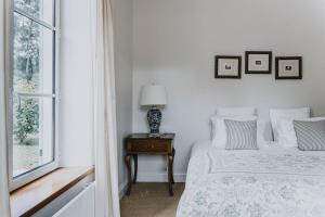 a white bedroom with a bed and a window at The French House in Trentham