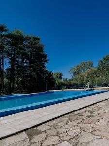 uma grande piscina com água azul e árvores em Hotel El Libertador em La Falda