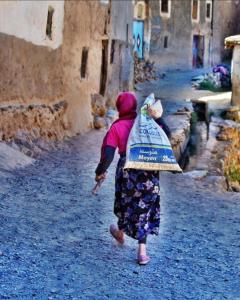Una mujer caminando por una calle con una bolsa en la espalda en DAR Awlim en Amassa