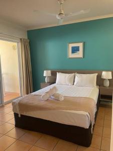 a bedroom with a large bed with a blue wall at Shingley Poolside Retreat in Airlie Beach