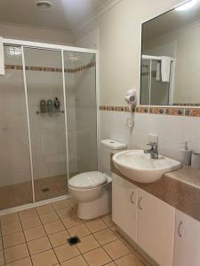 a bathroom with a toilet and a sink and a shower at Shingley Poolside Retreat in Airlie Beach