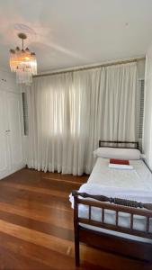 1 dormitorio con 1 cama con cortinas blancas y lámpara de araña en Apartamento vista mar!, en Salvador