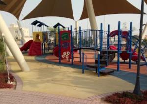 un parque infantil con tobogán y sombrilla en MBZ - Cosy Separate Room in Unique Flat, en Abu Dabi