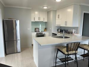 a kitchen with white cabinets and a sink and a refrigerator at Seaside Wanaka Tce in New Plymouth