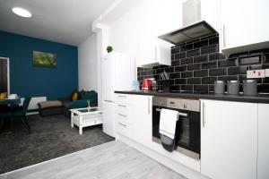 eine Küche mit weißen Schränken und einer schwarzen Ziegelwand in der Unterkunft 2 Bed Apartment! Near City Centre! 5 Guests*Long stay discount* in Cardiff