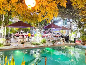 a swimming pool with people sitting around a restaurant at Hung Vuong Hotel in Tuy Hoa