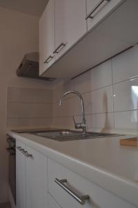 a kitchen with a sink and white cabinets at Apartments Peloža in Poreč