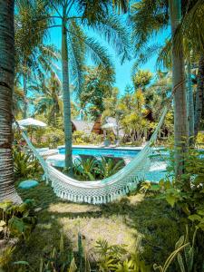 a hammock in a resort with a pool and palm trees at Selvática in Gili Islands