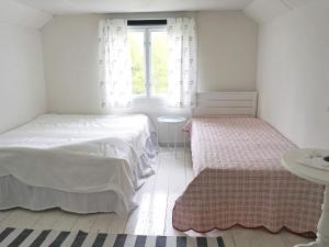 a white bedroom with two beds and a window at Holiday home HALLABRO IV in Hallabro