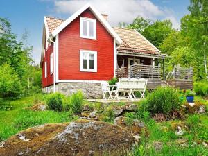 a red house with two white chairs in front of it at Holiday home HALLABRO IV in Hallabro
