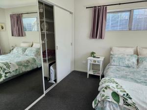een slaapkamer met 2 bedden en een spiegel bij Mangawhai Modern in Mangawhai