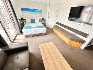 a bedroom with a bed and a tv and a couch at Top of the Town Motor Inn in Narooma