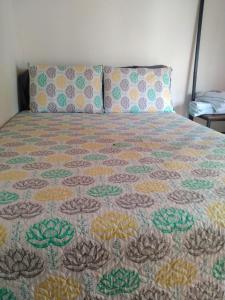 Una cama con una colcha colorida y almohadas. en Galilea en Santa Elena
