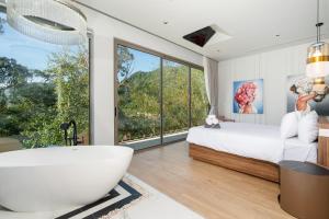 a bedroom with a tub and a bed and a large window at Himmapana Villas - Hills in Kamala Beach