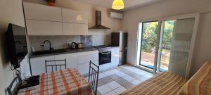 a kitchen with white cabinets and a table and a dining room at Apartments Antica in Basina