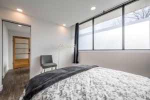 Schlafzimmer mit einem Bett, einem Stuhl und Fenstern in der Unterkunft Modern Contemporary 2 Bedroom Suite in Halifax