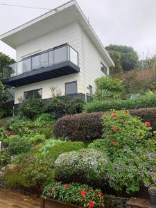 PACIFIC PARADISE COTTAGE في توتوكاكا: البيت الأبيض مع شرفة وبعض الزهور