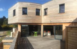 a house with a deck with a table on it at Hôtel des Rochers in Perros-Guirec