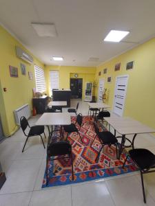 a dining room with tables and chairs on a rug at Check Inn Hostel in Almaty