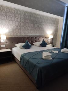 een slaapkamer met een groot bed met blauwe kussens bij De Marco Hotel in Qostanaj