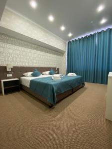 een slaapkamer met een bed en een blauw gordijn bij De Marco Hotel in Qostanaj