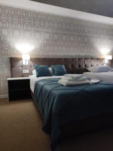 a hotel room with two beds and two lamps at De Marco Hotel in Kostanay