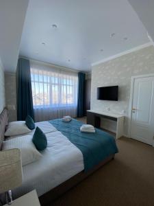a large bedroom with a large bed and a television at De Marco Hotel in Kostanay