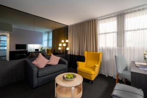 a living room with a couch and a yellow chair at Park Regis City Centre in Sydney