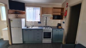 a small kitchen with a stove and a sink at Banana Coast Caravan Park in Coffs Harbour