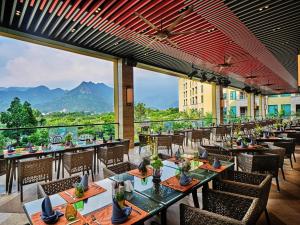 un restaurante con mesas y sillas con montañas al fondo en Regal Palace Resort & Spa, en Guangzhou