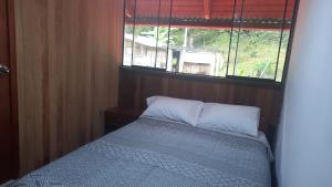 Dormitorio pequeño con cama y ventana en Cabañas del bosque Don Efraín-La Merced, en La Merced