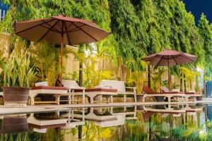 a group of chairs and umbrellas next to a pool at Monoreach Angkor Hotel in Siem Reap